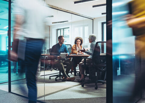 Three people having a conversation in a meeting room.